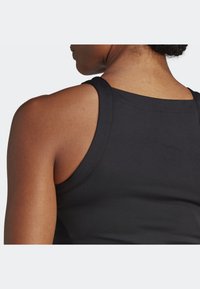 Schwarzes ärmelloses Tanktop mit glatter Textur, ausgestattet mit breiten Schulterträgern und einem runden Halsausschnitt, der den Schulterbereich betont.