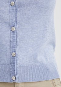 Lichtblauwe cardigan met een geribbelde structuur, zes decoratieve knopen die op edelstenen lijken aan de voorkant, en een geribbelde zoom voor een gestructureerde pasvorm.