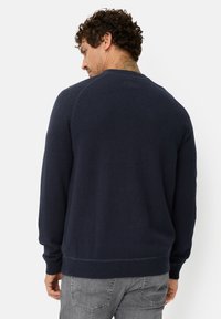 Navy blue knit sweater featuring a round neck, long sleeves, ribbed hem and cuffs, and a smooth texture with raglan sleeve design.