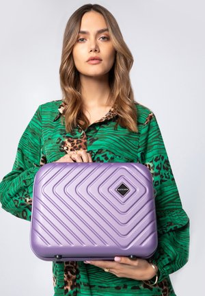 Purple suitcase with a textured, ridged design and a diamond logo. Features a durable exterior and a sturdy handle for carrying.