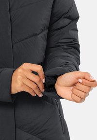 Black puffer jacket with quilted design, showing the cuff with elastic trim. The fabric appears smooth and lightweight.