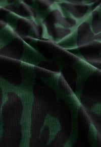 Sötétzöld és fekete leopárdmintás bordázott anyag. Az anyag finom vonalakat mutat, különálló mintázatvariációkkal a színekben.