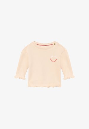 Maglietta per bebé a maniche lunghe color crema con polsini e orlo arricciati, ricamo floreale con faccina sorridente sul petto e dettaglio con bottoni sulla spalla.