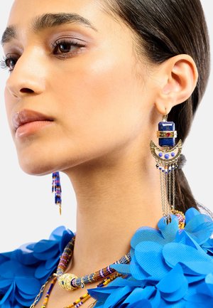 Auffälliger Ohrring in Lapislazuli-Blau und Gold mit geometrischem Design, verziert mit Ketten und mehrfarbigen Perlenakzenten. Sichtbare filigrane Handwerkskunst.