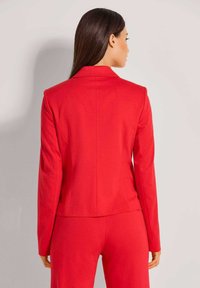 Rode getailleerde blazer van gladde stof, met een gesneden revers, lange mouwen en een op maat gemaakt ontwerp met subtiele plooien aan de achterkant.