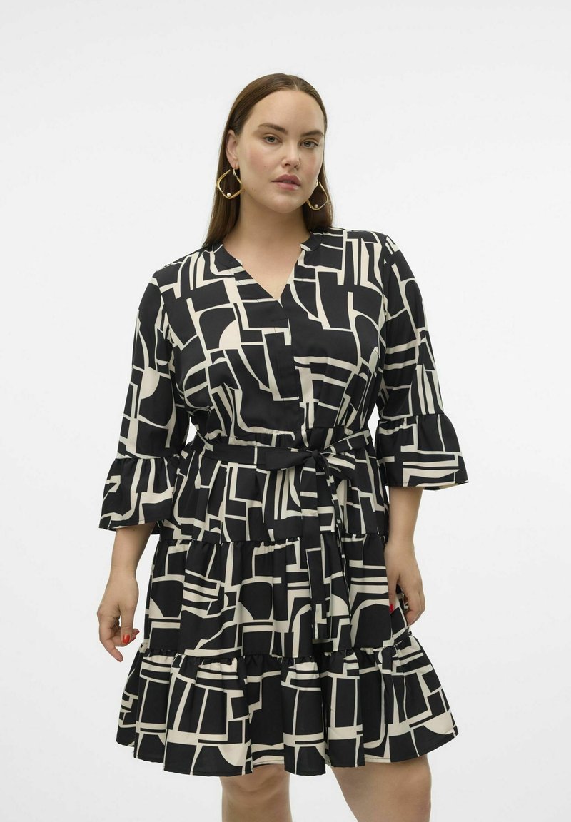 Robe noire et crème à motifs avec un col en V, volants superposés et manches ballon, cintrée à la taille avec une ceinture assortie.