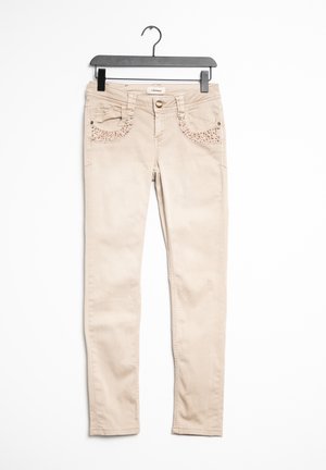 Jeans skinny beige con una texture liscia, con borchie decorative in oro rosa sulle tasche anteriori e chiusura con bottone.