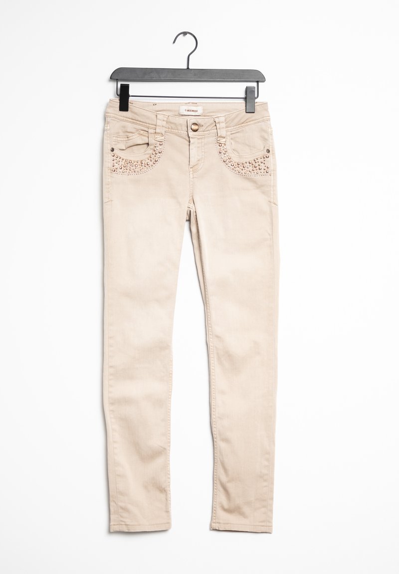 Jean skinny beige à texture lisse, avec des clous décoratifs en or rose sur les poches avant et une fermeture à bouton.