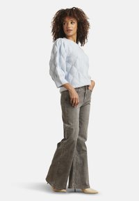 Light blue knitted sweater with a diamond pattern and three-quarter sleeves, paired with gray flared jeans and beige shoes.