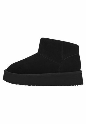 Bottines en suede noir avec une semelle en caoutchouc plate, présentant un bout rond et un design minimaliste. Texture lisse avec une silhouette simple et épurée.