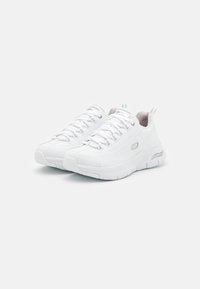 White athletic shoes with a smooth synthetic upper, lace closure, padded collar, and rubber sole with a slight heel lift.