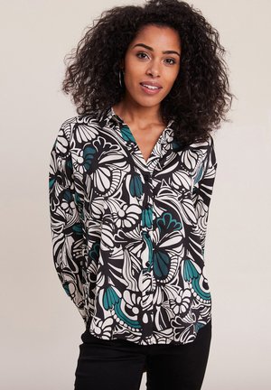 Blusa a maniche lunghe con motivo in bianco e nero e dettagli in teal, colletto e chiusura frontale con bottoni, caratterizzata da forme floreali e astratte.