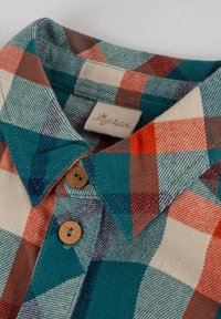 Camicia a quadri con colletto, nei colori turchese, arancione e crema. Bottoni in legno e un'etichetta tessuta aggiungono dettagli al tessuto.