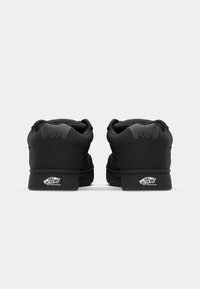 Zwarte leren sneakers met een gewatteerde kraag, ronde neus, dikke zool en het Vans-logo op de hiel, met een subtiel geruit patroon op de achterkant.