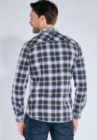 Karierte Flanellhemd in Marineblau, Beige und Hellblau. Button-Down-Kragen, lange Ärmel und einen abgerundeten Saum mit Details an der Vorder- und Rückseite.