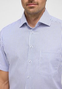 Korte mouwen knoopshirt met verticale blauwe en witte strepen, een gestructureerde kraag en een borstzak. Gemaakt van lichtgewicht stof.