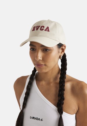 Beige stribet kasket med RVCA-logo, med en buet skygge og justerbar rem. Bæres med en hvid top, der fremviser en fletning.
