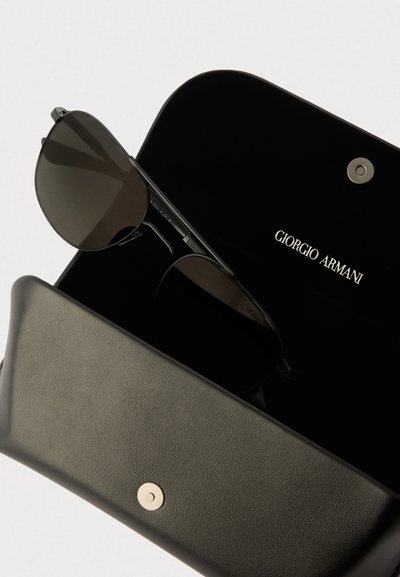 Giorgio Armani solbriller i et svart etui. Solbrillene har mørke linser, tynne metallrammer, og er plassert inne i et mykt, teksturert etui.