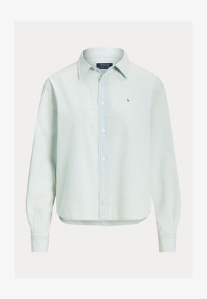 Gaiši zils garām piedurknēm krekls ar pogām un apkakli, mazs izsistais logo kreisajā krūtī un Polo Ralph Lauren etiķete apkakles iekšpusē.