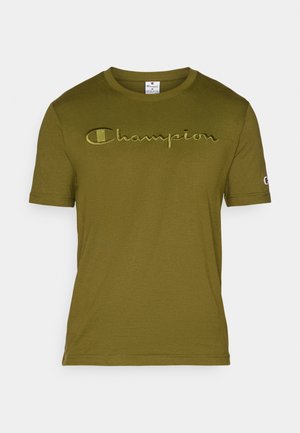 T-shirt verde oliva a maniche corte con la scritta "Champion" ricamata sul petto e un piccolo patch con il logo sulla manica sinistra.