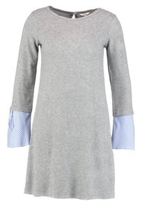 Grå klänning med långa ärmar, med blå och vita randiga manschetter. Tillverkad av mjukt tyg, med rundad halsringning och en avslappnad passform.
