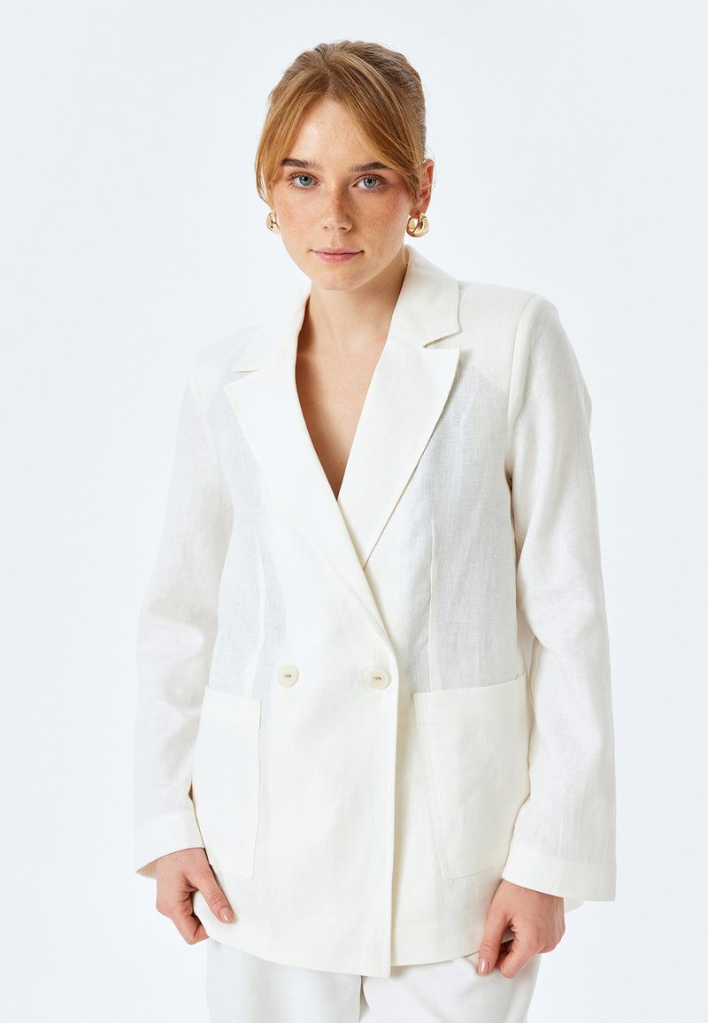 Witte dubbel-breasted blazer van linnen, met gekleurde revers, twee voorzakken en een ontspannen pasvorm. Soepele textuur en lichte kleur.