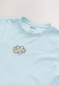Hellblaues Baumwoll-T-Shirt mit Rundhalsausschnitt. Mit einem grafischen Logo und dem Text "NIRVANA In Bloom" in mehrfarbiger, verspielter Schrift.