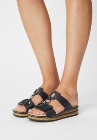 Sandali wedge neri in pelle, con fibbia decorativa, design con punta aperta, suola in sughero testurizzato e piattaforma stratificata per un'altezza extra.