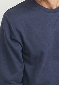 Felpa a maniche lunghe di colore blu navy in morbido cotone misto, con scollatura rotonda e design senza cuciture sulle spalle, tessuto testurizzato.