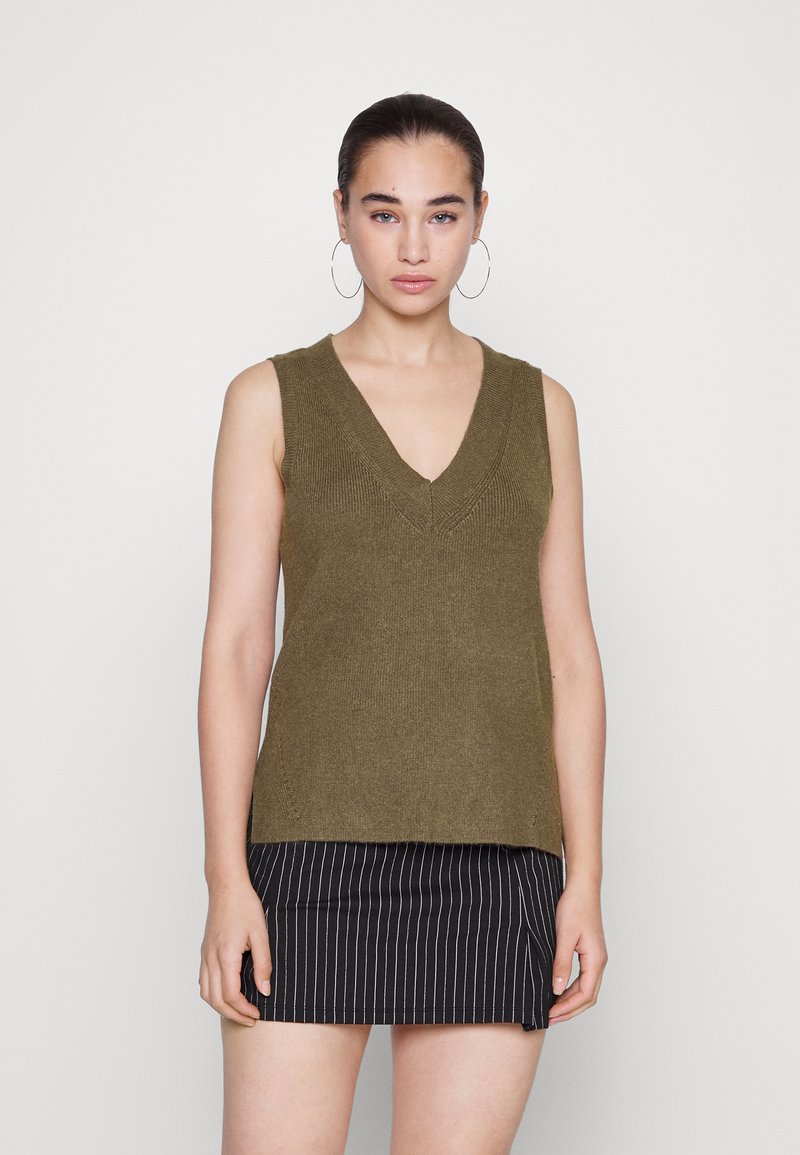 Top de malha sem mangas em verde-azeitona com um profundo decote em V e detalhes texturizados, combinado com uma saia preta às riscas.