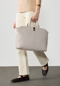 Light gray leather tote bag with dual handles, a gold-tone accent, and a structured design. Smooth texture and spacious interior.