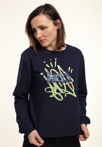 Felpa blu navy con maniche lunghe, caratterizzata da un design di graffiti stampato in verde e rosso, inclusa un'illustrazione di un camion.
