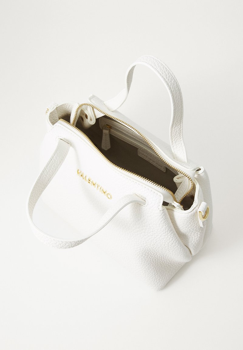 Bolso de mano de cuero blanco con una textura de piel de melocotón, detalles en hardware dorado, cierre superior con cremallera y dos asas resistentes. La vista interior muestra un forro claro.