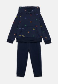 Tumši zila kapucīna krekla un bikses komplekts ar daudzkrāsainām izšūtām krokodila emblēmām, kas izkaisītas pa krekla virsmu.