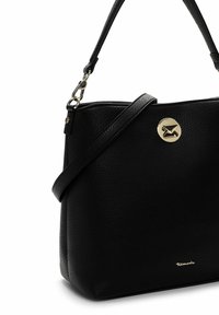 Juodos tekstūruotos odos rankinė su reguliuojamu peties dirželiu, auksiniu sukamu užsegimu ir mažu auksiniu "Tamaris" logotipu prie apačios.