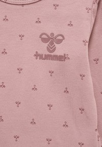 Jasnoróżowy sweatshirt z teksturowanym wzorem małych kwiatków, z wypukłym logo w ciemniejszym odcieniu, okrągłym dekoltem i miękkim materiałem.