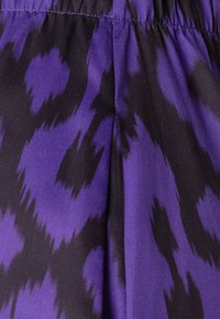 Tessuto viola e nero con motivo a stampa leopardata, texture liscia con una leggera lucentezza, dettaglio di cucitura a vita arricciata.