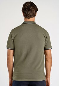 Olivgrön pikétröja med korta ärmar, en platt krage med marinblå och vita ränder samt en strukturerad tyg.