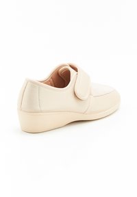 Scarpe beige con tomaia in tessuto testurizzato, fasce in Velcro, punta arrotondata e suola a zeppa bassa. Fodera interna liscia per il comfort.