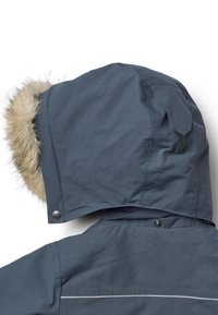 Giacca impermeabile grigia con cappuccio foderato in pelliccia. Caratteristiche includono chiusura a scatto e una sottile striscia riflettente lungo il davanti.