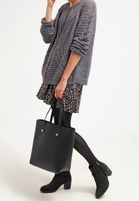 Gray knit sweater with textured pattern, black floral skirt, black leggings, black leather tote bag, and black ankle boots.
