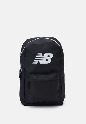 Czarny plecak z przednią kieszenią na zamek, białą lamówką u góry oraz dużym białym logo New Balance z przodu.