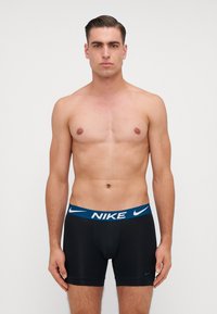 Pánske čierne boxerky s modrým pásom a logom "NIKE". Hladká tkanina s tesným strihom a bez viditeľných vzorov či ozdôb.