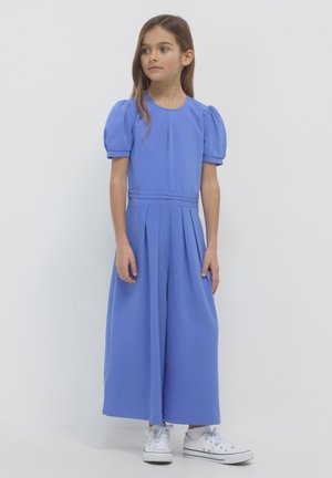 Blauer Jumpsuit mit Puffärmeln, gepuffter Optik und taillierter Taille. Kombiniert mit weißen Sneakers, aus einem glatten, leichten Stoff gefertigt.