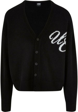 Svart stickad cardigan med v-ringad design, knappstängning och ribbade ärmslut. Broderad vit text på vänster sida, kort passform.