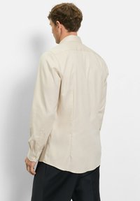 Beiges Hemd mit langen Ärmeln aus strukturiertem Stoff, spitzem Kragen und knöpfbaren Manschetten, ausgestattet mit geradem Saum und Rückenpasse.