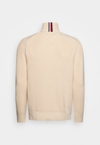 Pull en tricot couleur crème avec un col haut, présentant des rayures verticales rouges, blanches et bleu marine, vu de dos.