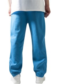 Pantaloni de trening bleu deschis cu un waistband elastic și manșete, fabricați dintr-un material moale. Textură netedă cu cusături laterale și detalii minime.
