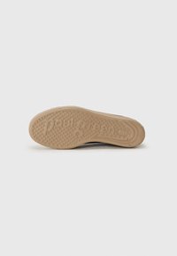 Shoe sole with a textured surface; light brown rubber material. Notable embossed brand name, circular patterns for traction.