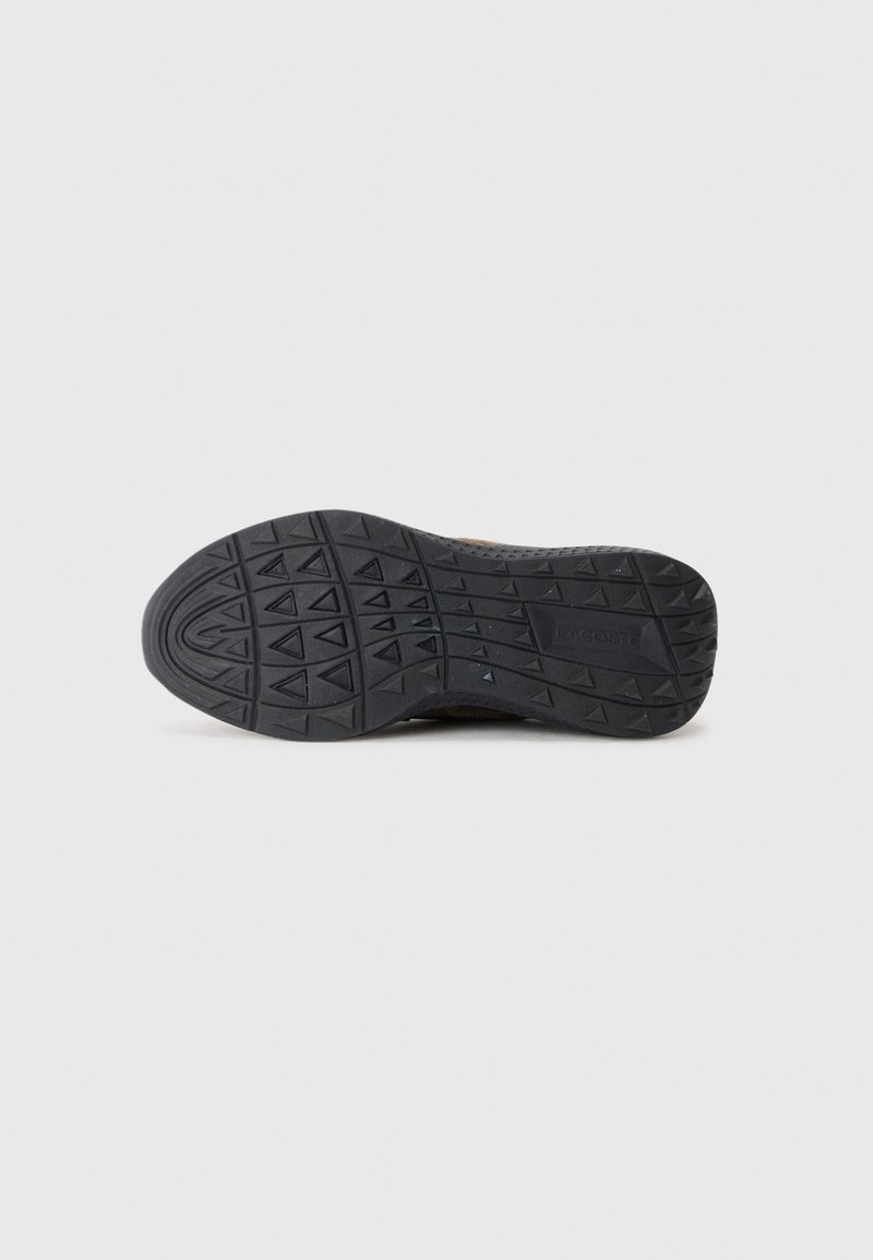 Schwarze Gummisohle eines Sneakers mit einem strukturierten Muster aus parallelen Linien und dreieckigen Formen. Logo auf der Seite deutlich sichtbar.